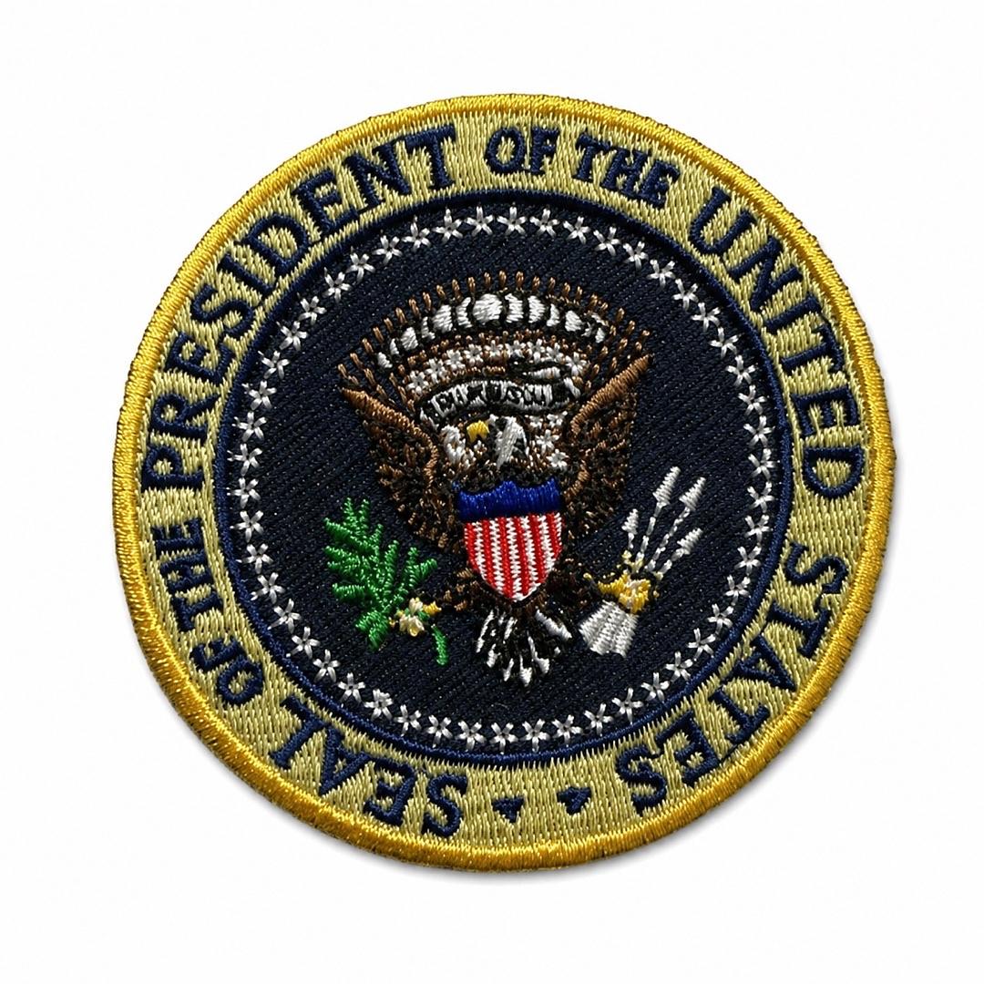 An embroidered circular patch featuring the United States Presidential Seal, with a gold border and a dark navy blue center containing the eagle, shield, and olive branch details.