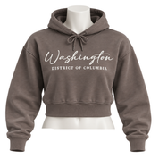 A cropped pullover hoodie in a muted taupe-brown color, displayed on a white mannequin torso. The hoodie features 'Washington' in white cursive script and 'DISTRICT OF COLUMBIA' in white block letters across the chest.