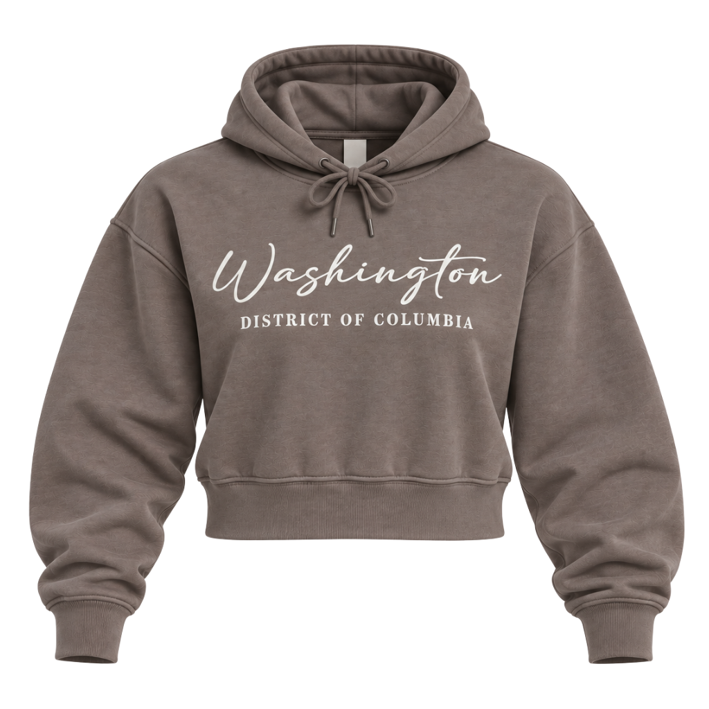 A cropped pullover hoodie in a washed taupe-brown color, featuring 'Washington' and 'DISTRICT OF COLUMBIA' printed in white script across the chest. The hoodie is shown against a plain white background.