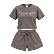 A two-piece' loungewear set in a dark grayish-brown color, featuring a short-sleeve t-shirt and matching shorts. The t-shirt has 'Washington District of Columbia' printed in white across the chest, and the shorts have a matching print on the lower left leg.