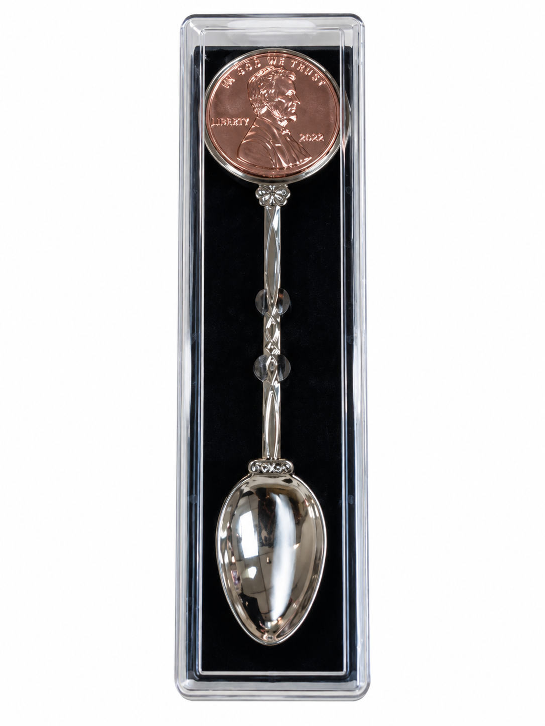 A silver spoon-shaped bookmark with a penny charm, presented inside a clear plastic protective case with a black insert, on a white background.