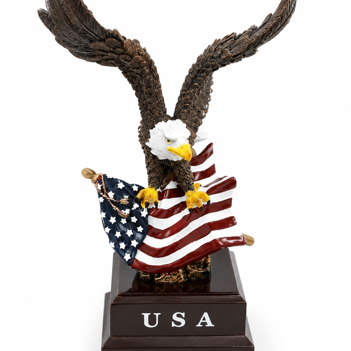 An eagle figurine with outstretched wings holding an American flag, mounted on a dark brown rectangular base engraved with 'USA'.