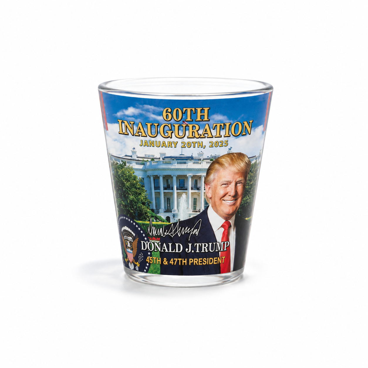 A clear glass shot glass featuring a printed design of Donald Trump's 60th inauguration, with a portrait of Donald Trump, the White House, and text reading '60TH INAUGURATION JANUARY 20TH, 2025'.