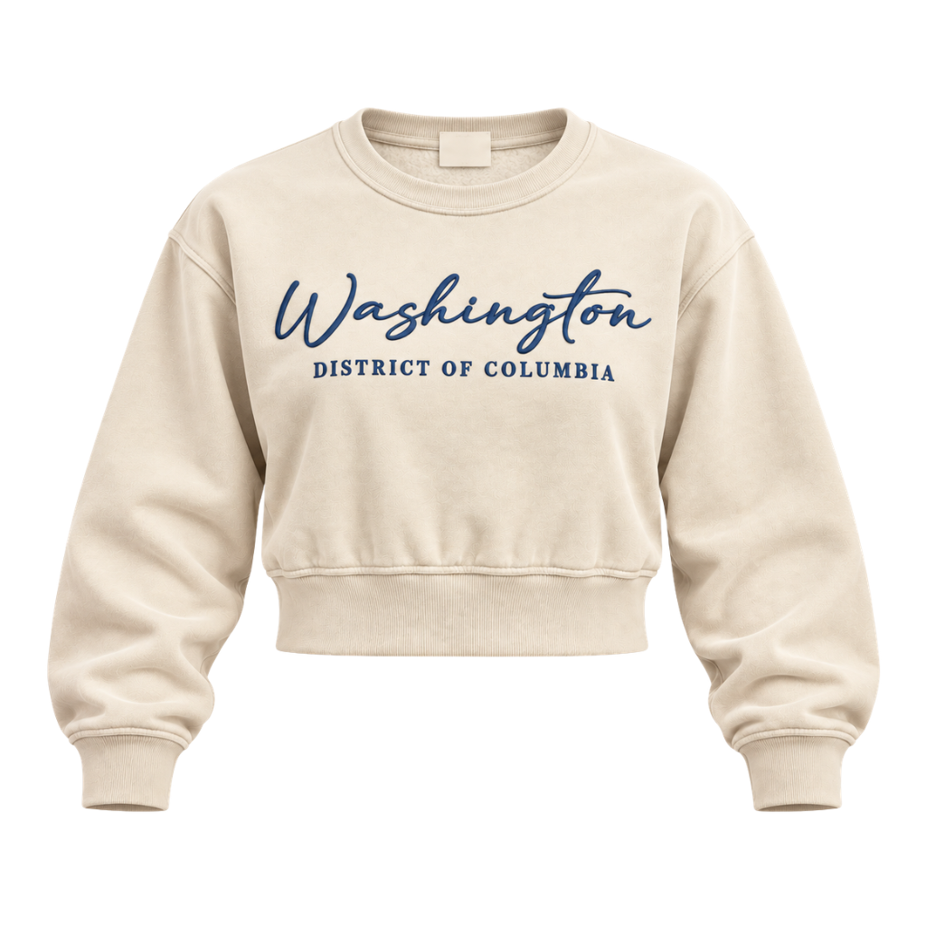 A cream-colored cropped crewneck sweatshirt with 'Washington District of Columbia' printed in navy blue across the chest, displayed on a clean white background.