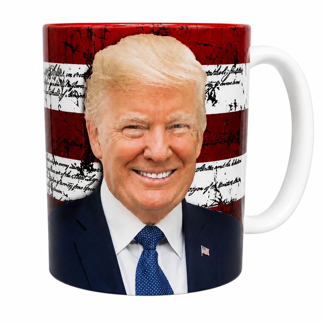 A white ceramic mug featuring a printed graphic of Donald Trump's smiling face over a distressed red, white, and blue American flag design with handwritten script details.
