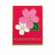 A rectangular enamel pin featuring a bright pink background with two flowers outlined in gold: a large pink blossom, a smaller white blossom, a green leaf, and the text 'WASHINGTON D.C.