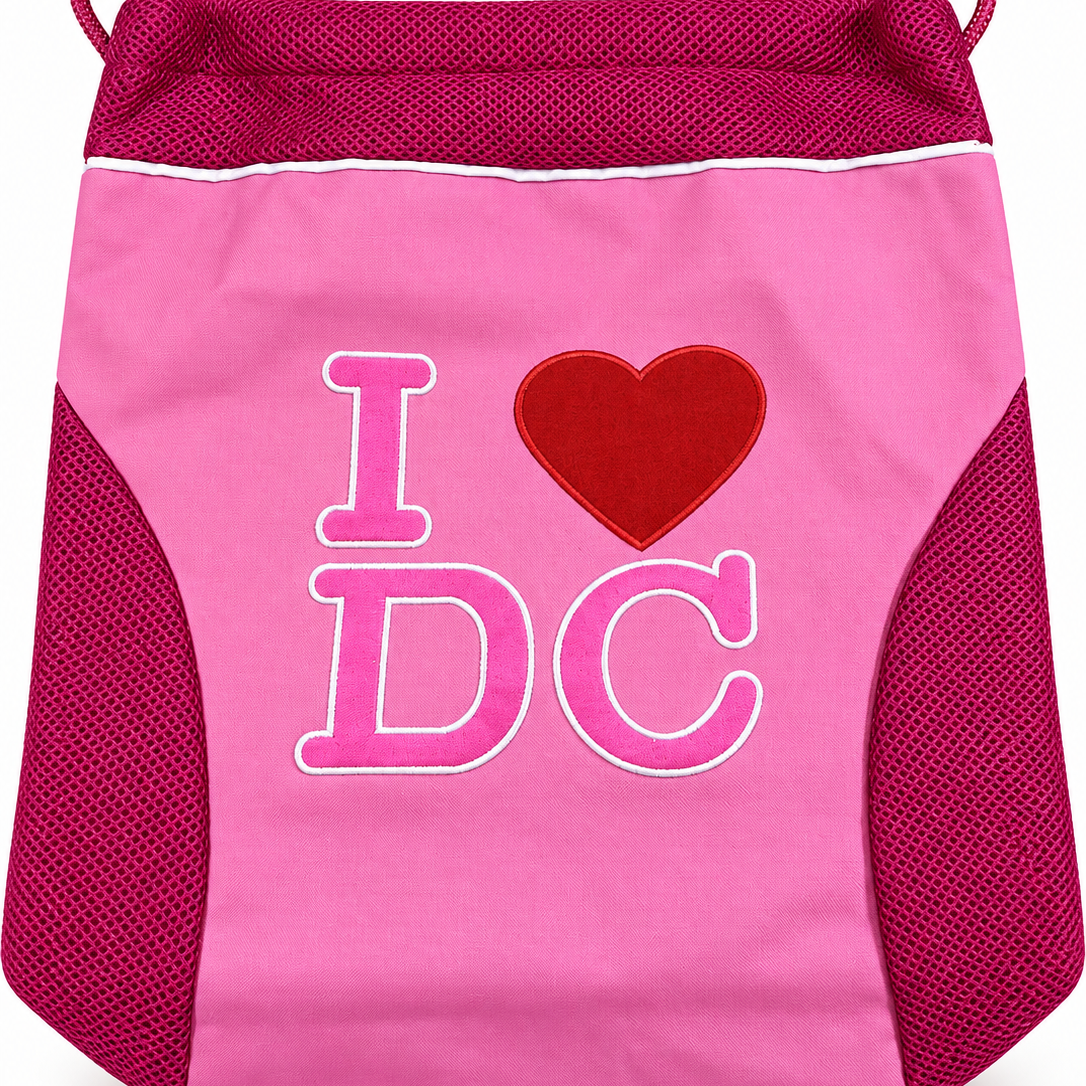 A pink drawstring bag with dark pink mesh side panels and top trim, featuring a red heart and the text 'I DC' in pink on the front.