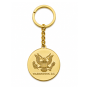 A gold-colored metal keychain featuring a round medallion with the Washington D.C.