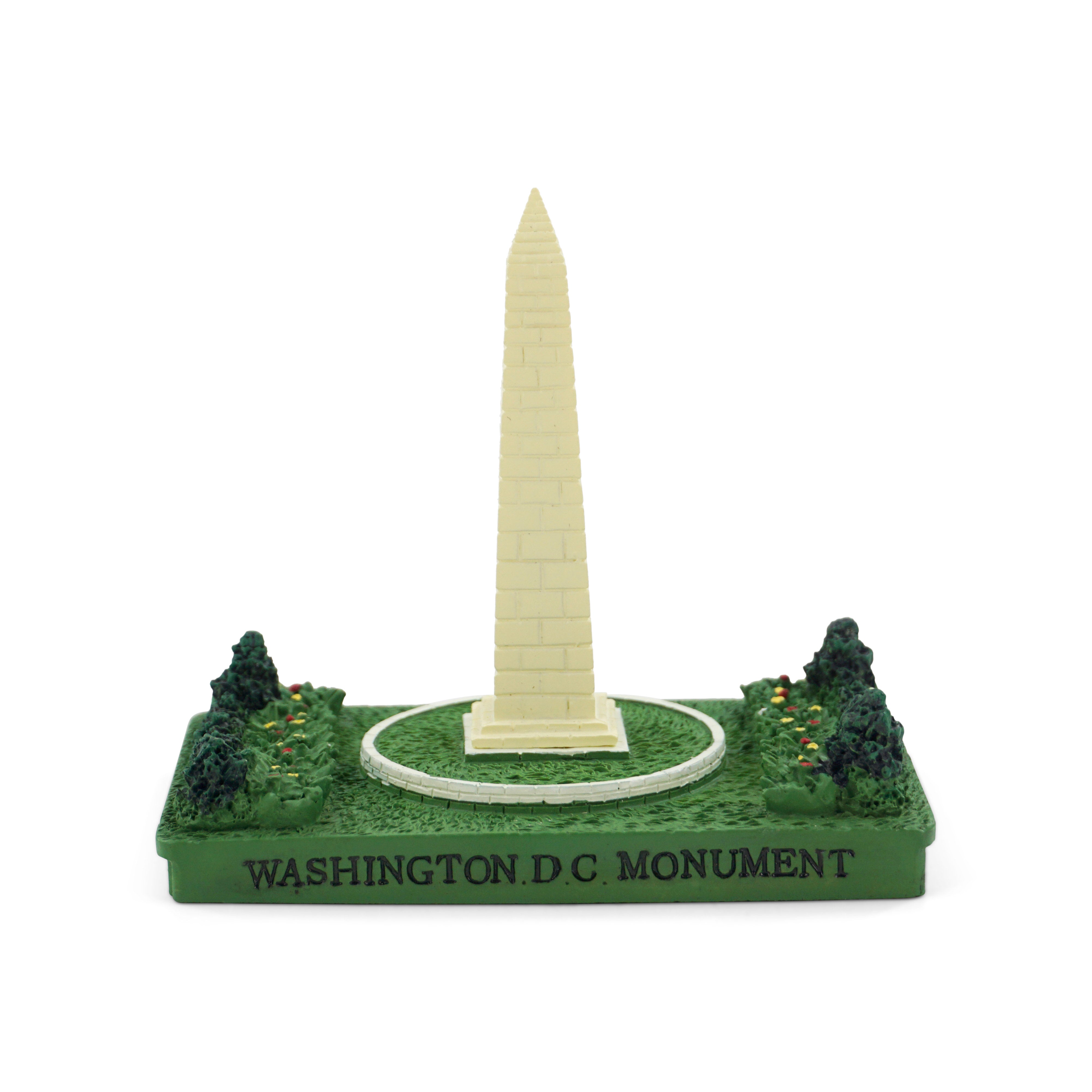 Model of the Washington Monument on a green base with trees, on a white background