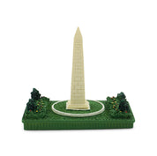 Model of the Washington Monument on a green base with trees