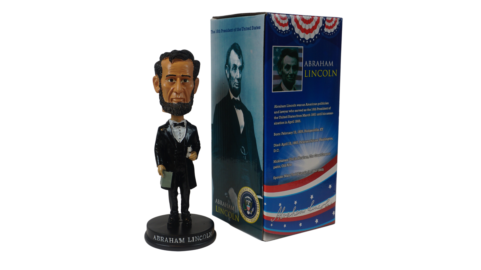 A black bobble head figurine of Abraham Lincoln, depicted in formal attire, placed in front of its packaging which features a biography and signature of the president.